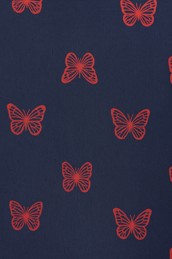A navy blue short-sleeved girl’s frock with red butterfly print and a gathered skirt.