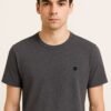Close-up of folded heather charcoal gray t-shirt with black embroidered DC logo on the corner
