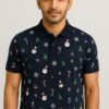 Man wearing navy blue polo shirt with Christmas-themed snowman, candy cane, snowflake, and tree patterns