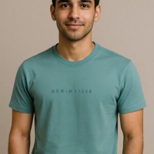 Man wearing a teal green T-shirt with minimalist “DENIM • 1998” text across the chest