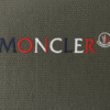 Close-up of Moncler logo embroidered on olive green textured t-shirt fabric