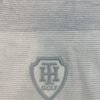 Short-sleeved polo shirt with horizontal grey and white stripes, ribbed collar, and embroidered crest logo.