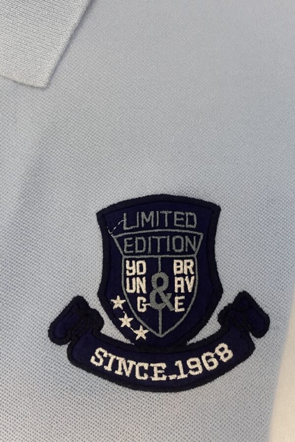 Folded light blue polo shirt with embroidered "Limited Edition Since 1968" crest on chest