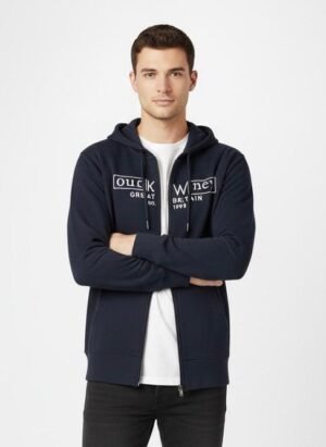 Men’s Navy Blue Zip-Up Hoodie with Logo Print Man wearing a navy blue zip-up hoodie with white printed logo, white t-shirt underneath, and black jeans, standing with arms crossed against a plain white background.
