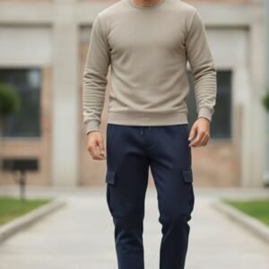 Beige ribbed crewneck sweatshirt displayed on a black hanger with a gold hook in a softly lit clothing store background.
