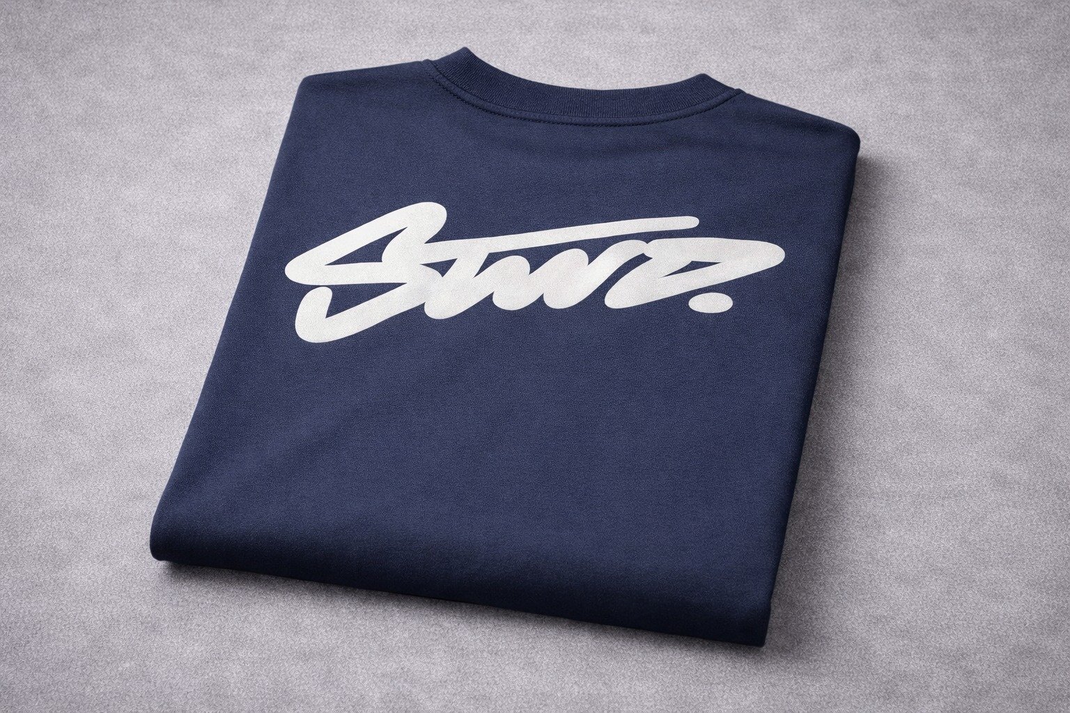 Back view of a man wearing a navy blue graphic T-shirt with a bold white script print on the back in an urban street setting.