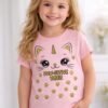 Young girl wearing a pink half sleeve t-shirt with cute cat unicorn face and paw prints graphic with “Paw-Sitive Vibes” text