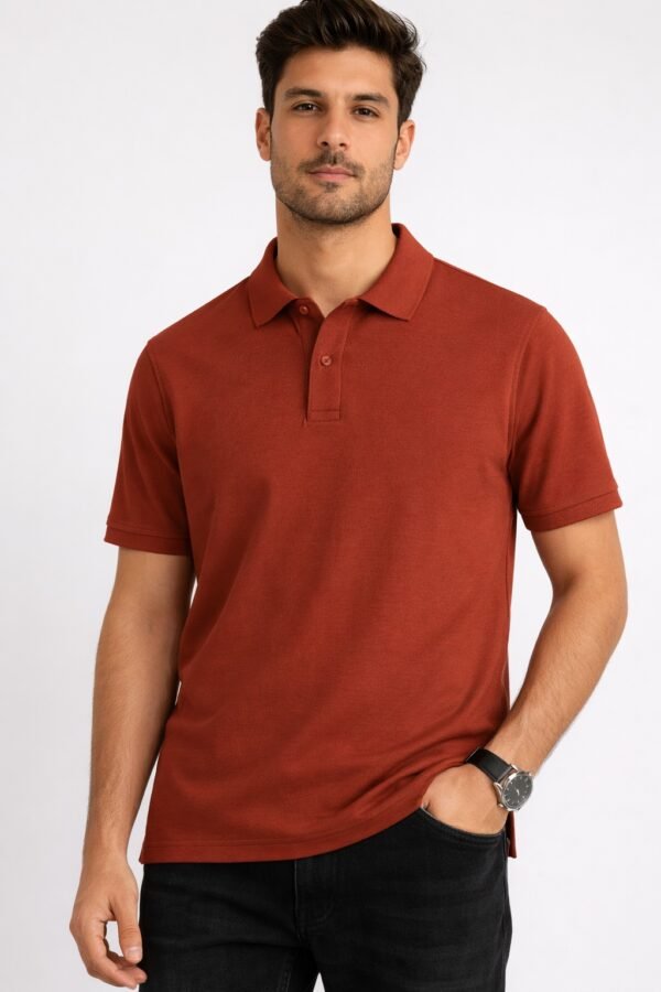 Man wearing a rust brown short-sleeve polo shirt with a collar and buttons, paired with black jeans, standing against a light grey background.